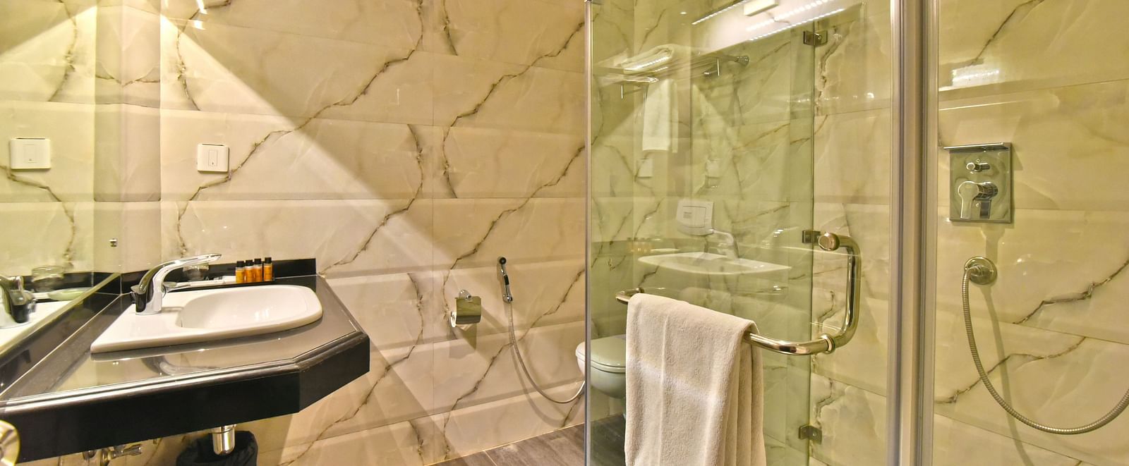A shower cubicle with a wash basin beside it at DLS Hillcrest Resort, Shimla.